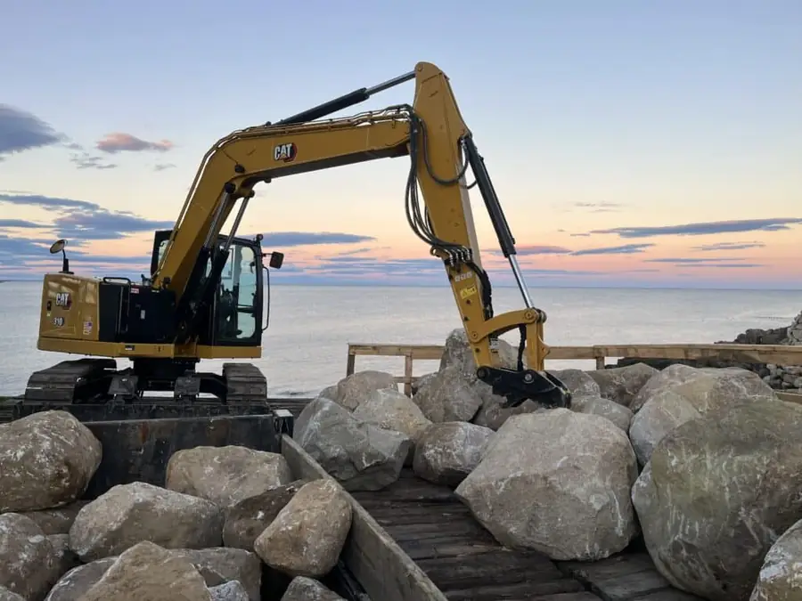 Excavator placing boulders along the shoreline
