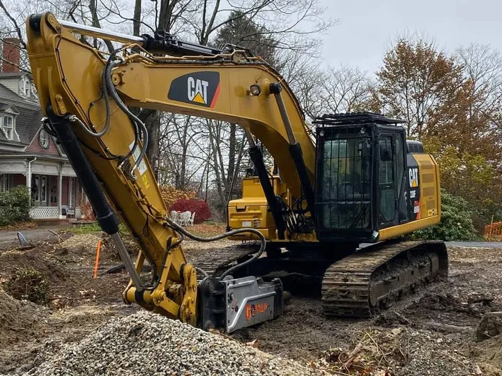 Yellow excavator working a residential dig with houses behind
