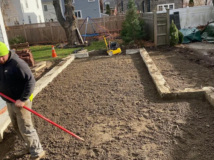 Worker with a tool leveling and packing a gravel bed