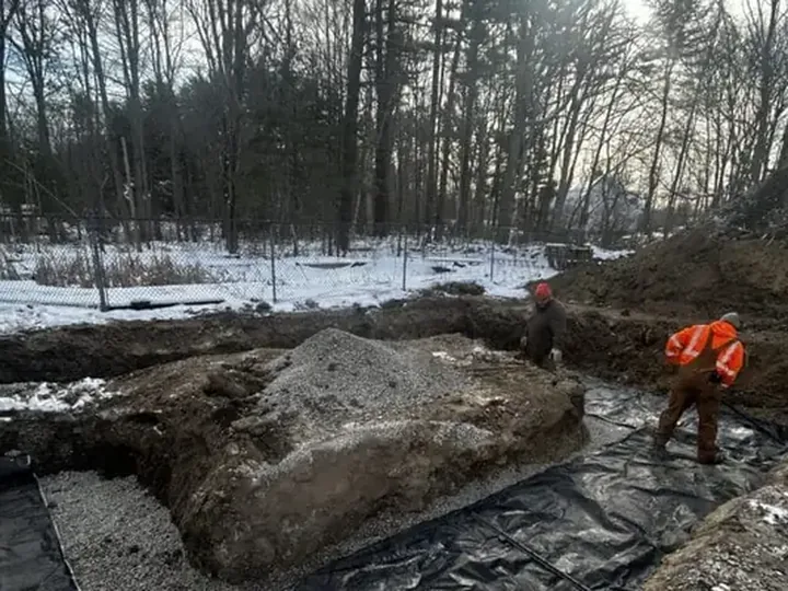 Crew working in an excavated area on a snowy wooded lot