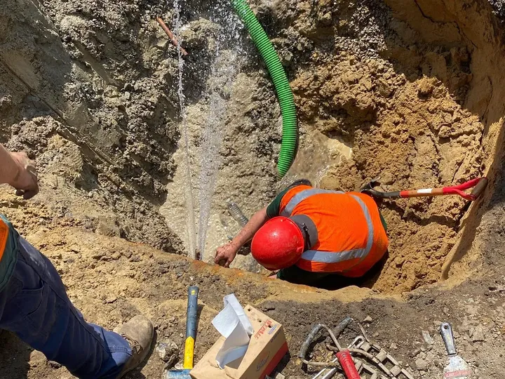 Crew down in an excavated hole working at a water line