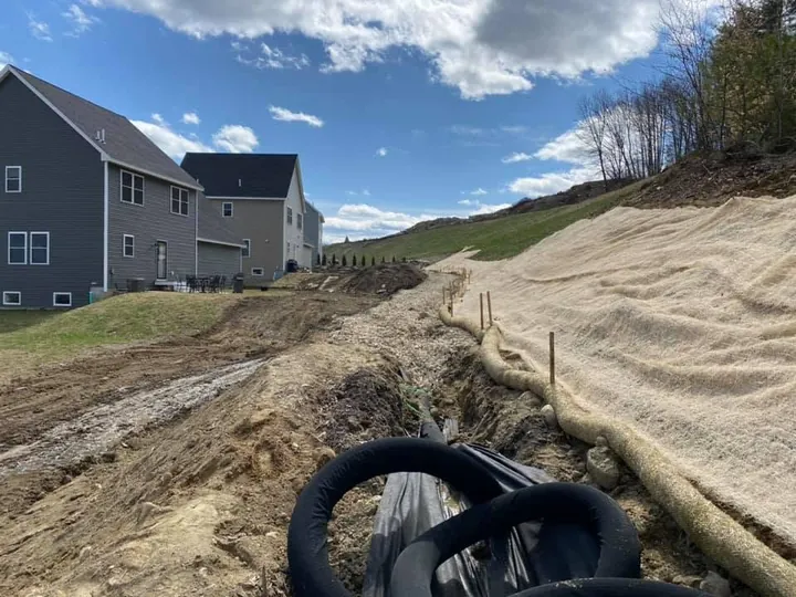 Black drain pipe in a trench running between two new houses