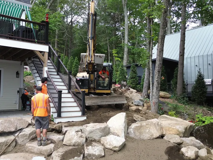 Aerial view of crew working boulder steps beside a lakefront house