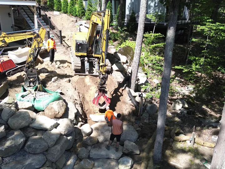 Drone view of two machines and crew moving stone on a slope