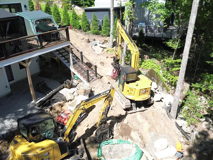 Aerial view of two excavators beside a house with a gravel filled area