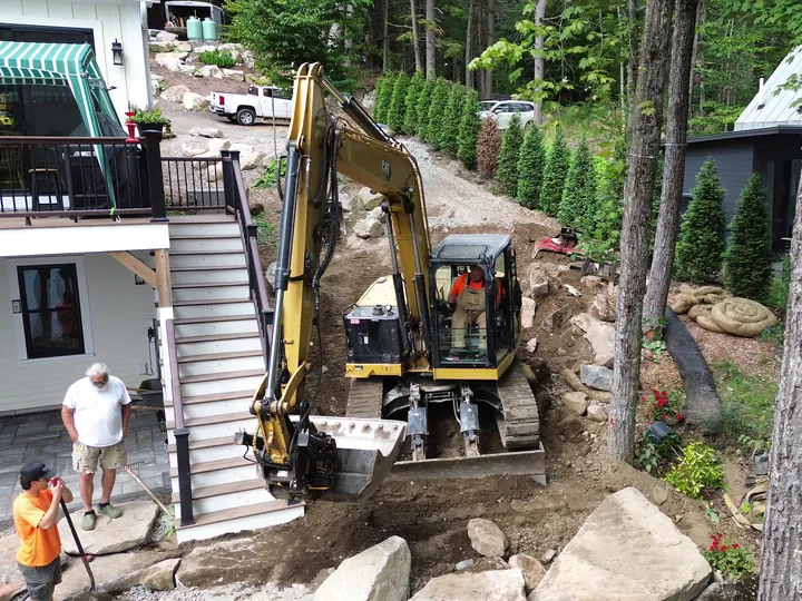 Drone view of a mini excavator at the bottom of a deck stairway