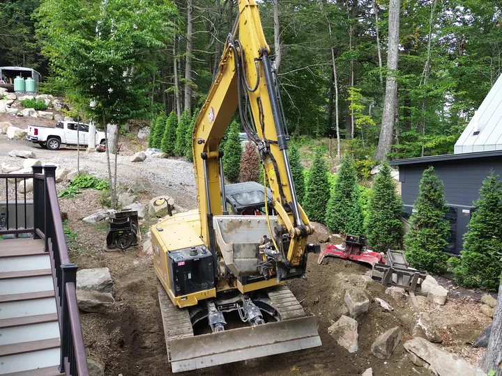 Drone view of an excavator on a slope beside a deck stairway