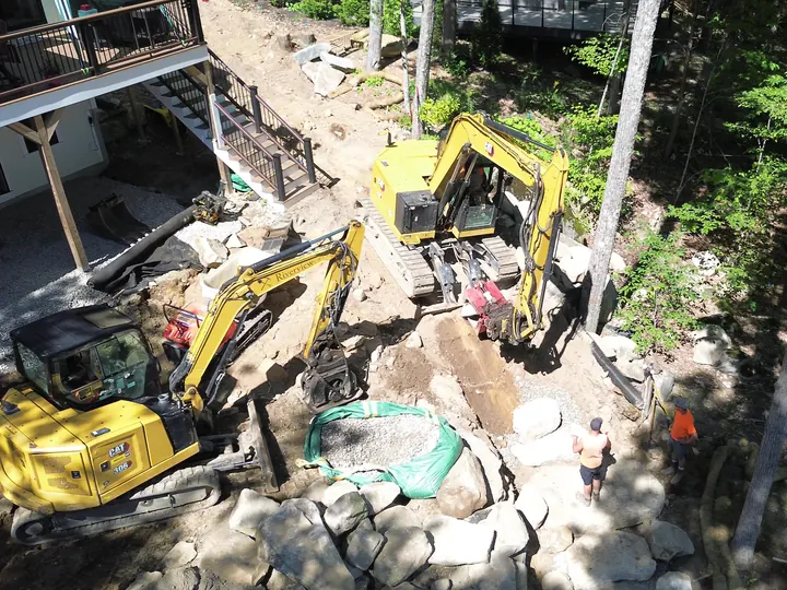 Aerial view of a gravel filled drainage area next to a house with two excavators