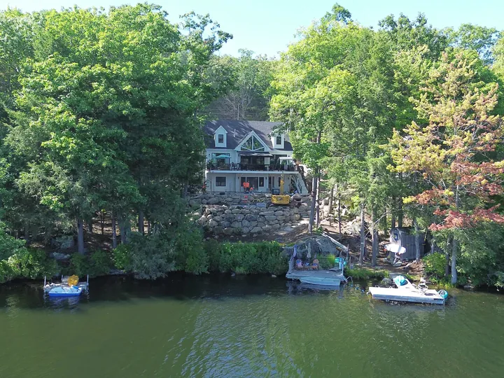 Drone view of a lakefront house and yard seen from over the water