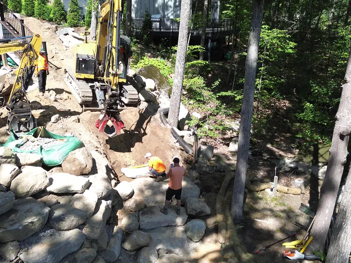 Drone view of excavators and crew working among large boulders