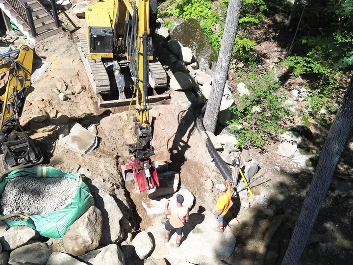 Drone view of machines at the base of a boulder wall