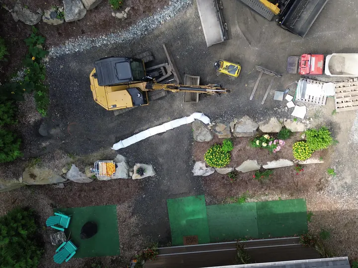 Top down aerial view of a track loader and materials staged on a gravel drive
