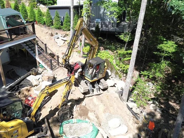 Drone view of a mini excavator working below a raised deck beside a house
