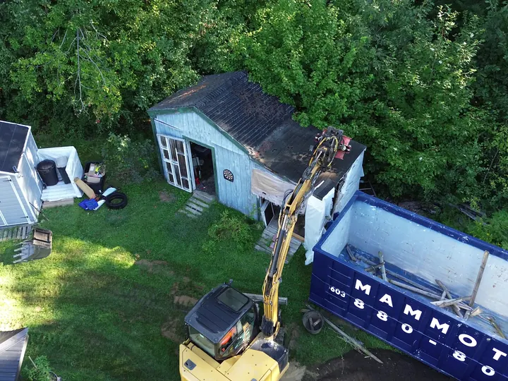 Aerial view of an old backyard shed next to a dumpster before the teardown