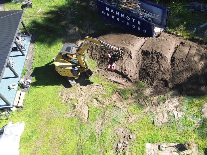 Top down aerial view of an excavator spreading fill across a yard