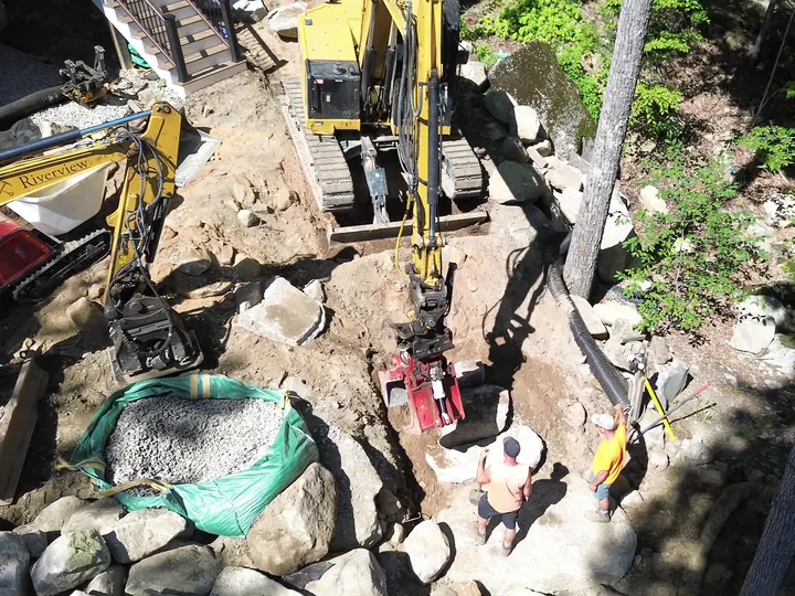 Aerial view of two excavators working a trench beside a house