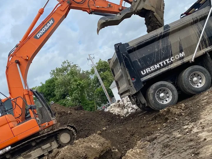 Excavator filling a dump truck from a sloped dig