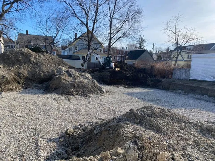Dug out residential lot with piles of soil and gravel between houses