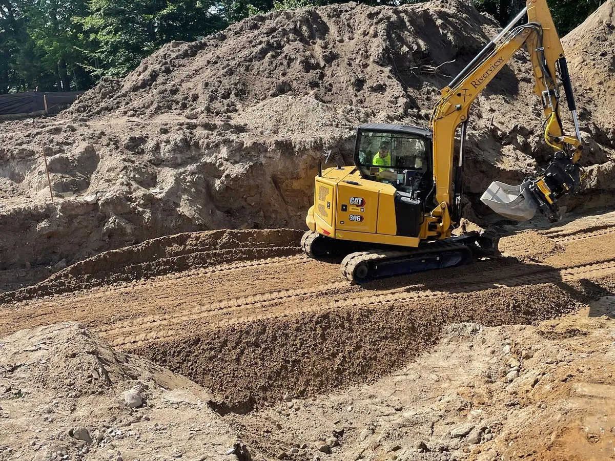 Mini excavator cutting the driveway into a sandy slope