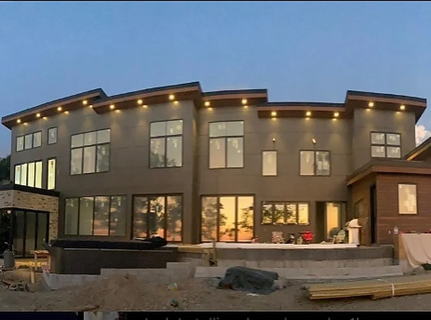 The finished lakefront home lit up at dusk