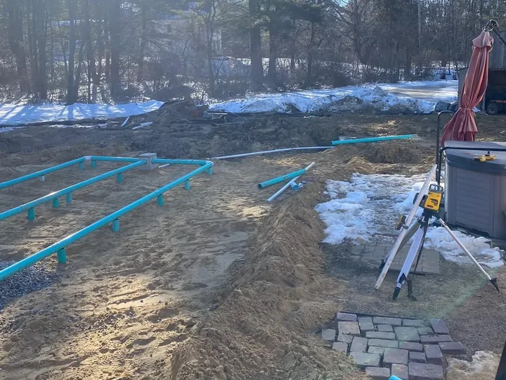 Tripod laser level set up beside new septic pipe