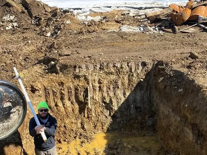 Worker at the bottom of a deep septic excavation
