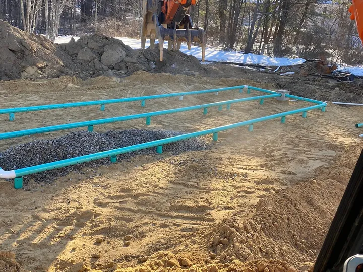 Green septic pipe runs laid across an excavated field