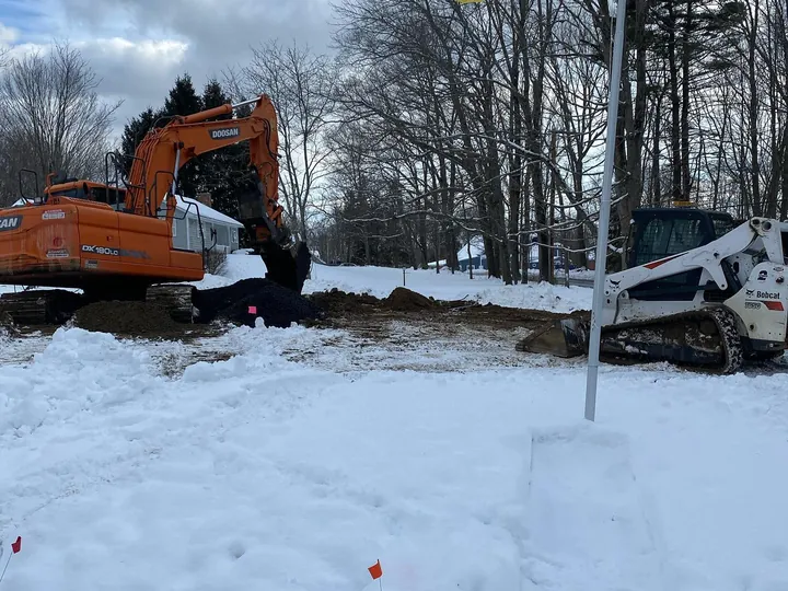 Snow covered work area with an excavator and skid steer standing by