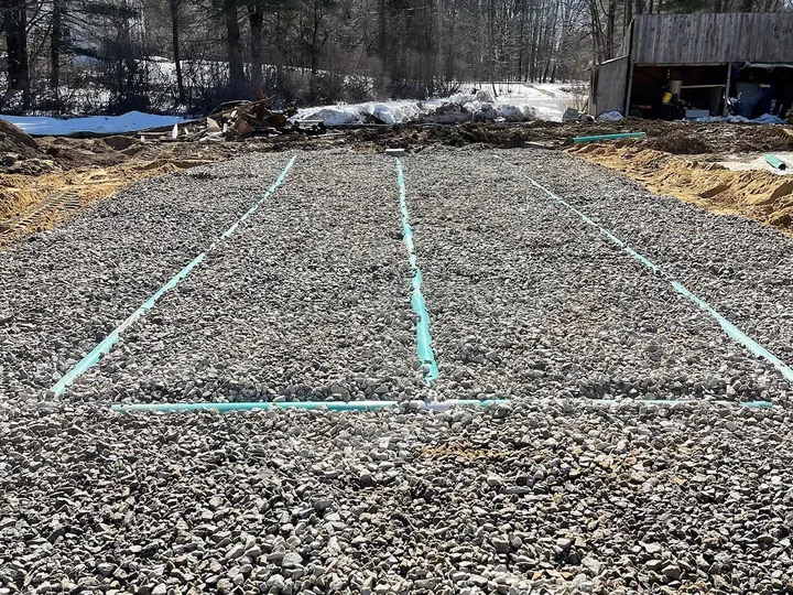 Septic field with green pipe surrounded by crushed stone