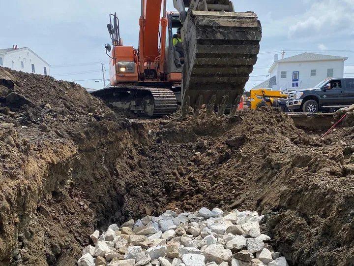 Crushed stone in the bottom of a deep excavation with an excavator above
