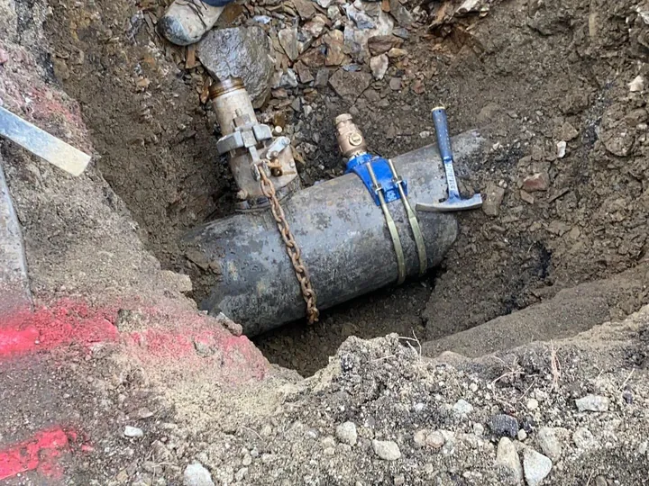 Large utility pipe exposed at the bottom of a rocky trench