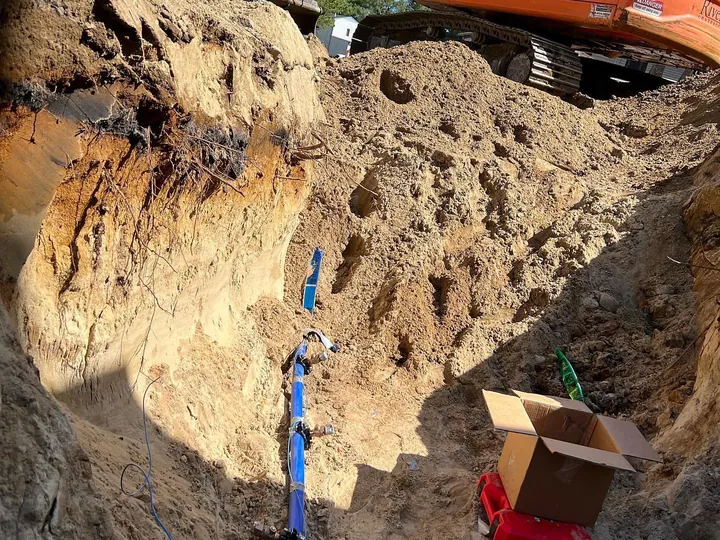 Deep trench with a blue service line running down the side